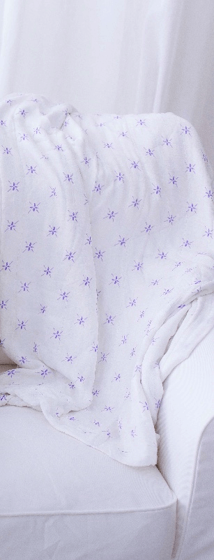 Watercolor Star Blanket draped over a white chair, featuring delicate purple star patterns.
