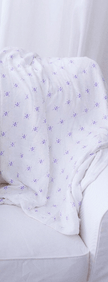 Watercolor Star Blanket draped over a white chair, featuring delicate purple star patterns.