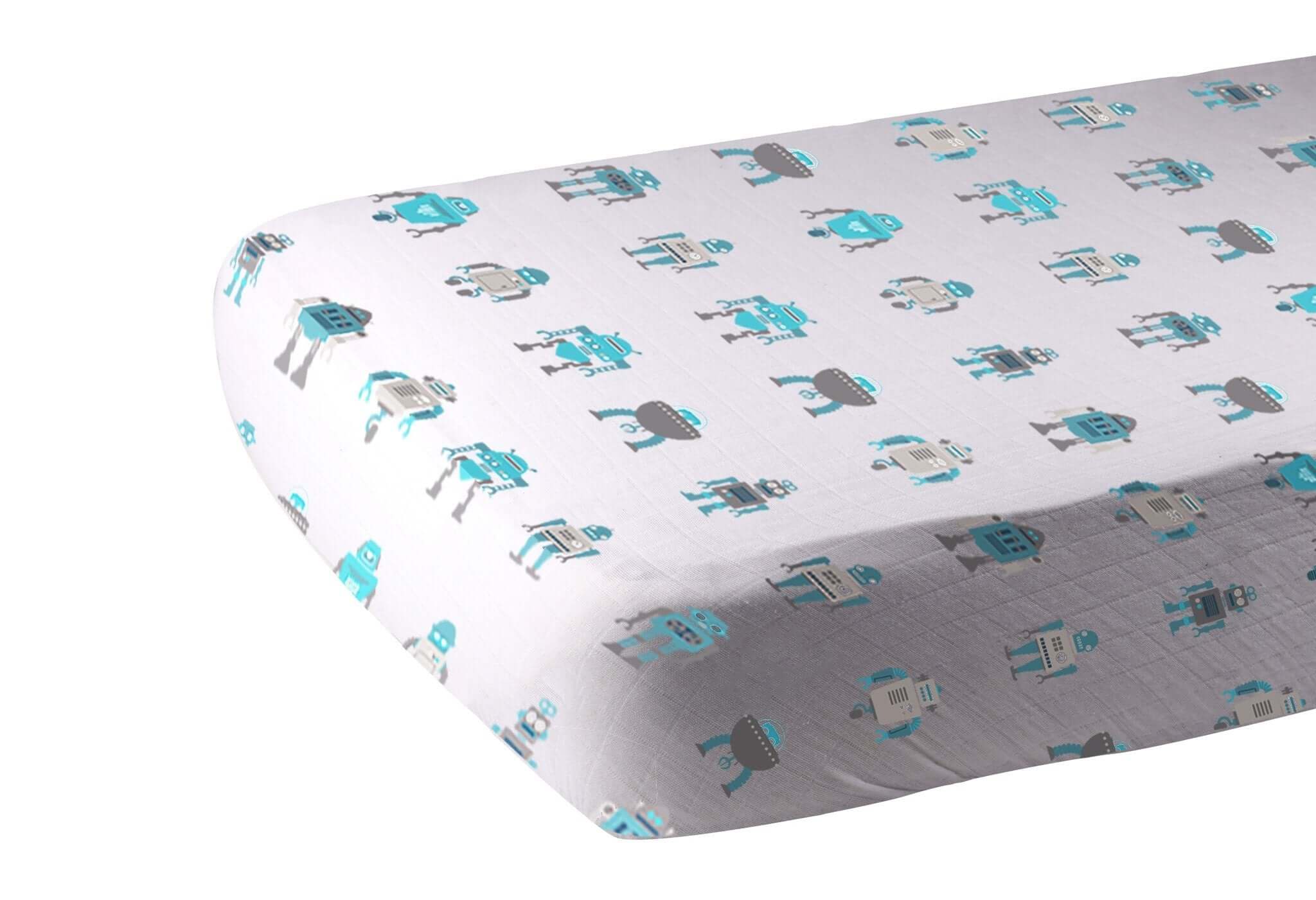 Cotton crib sheet with a playful robot pattern in blue and gray colors on a white background.