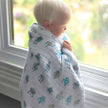 Cotton baby blanket wrapped around a child looking out the window, featuring playful robot designs.
