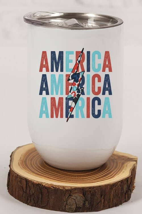 Patriotic USA Bolt Tumbler featuring the word 'America' in bright colors on a wooden surface.