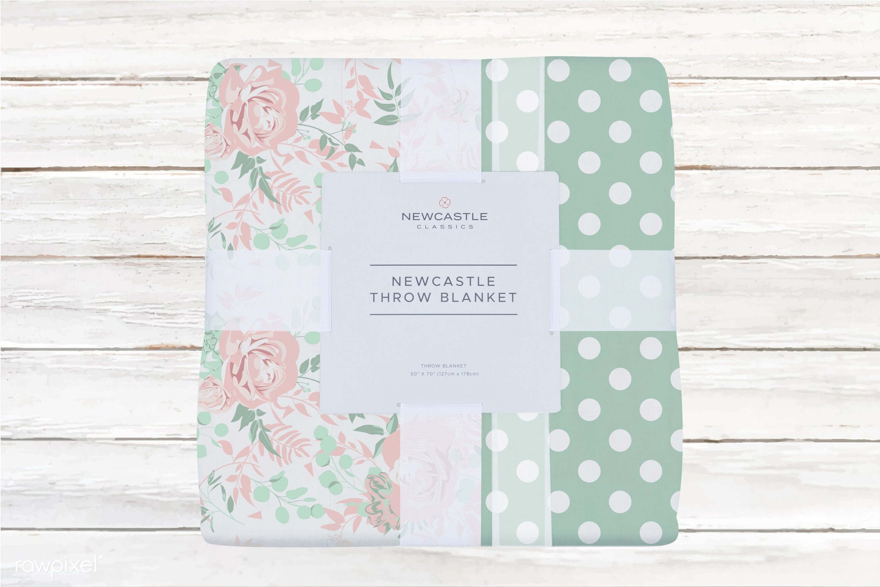 Newcastle throw blanket with floral design and polka dots on a rustic wooden background.