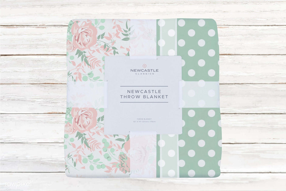 Newcastle throw blanket with floral design and polka dots on a rustic wooden background.