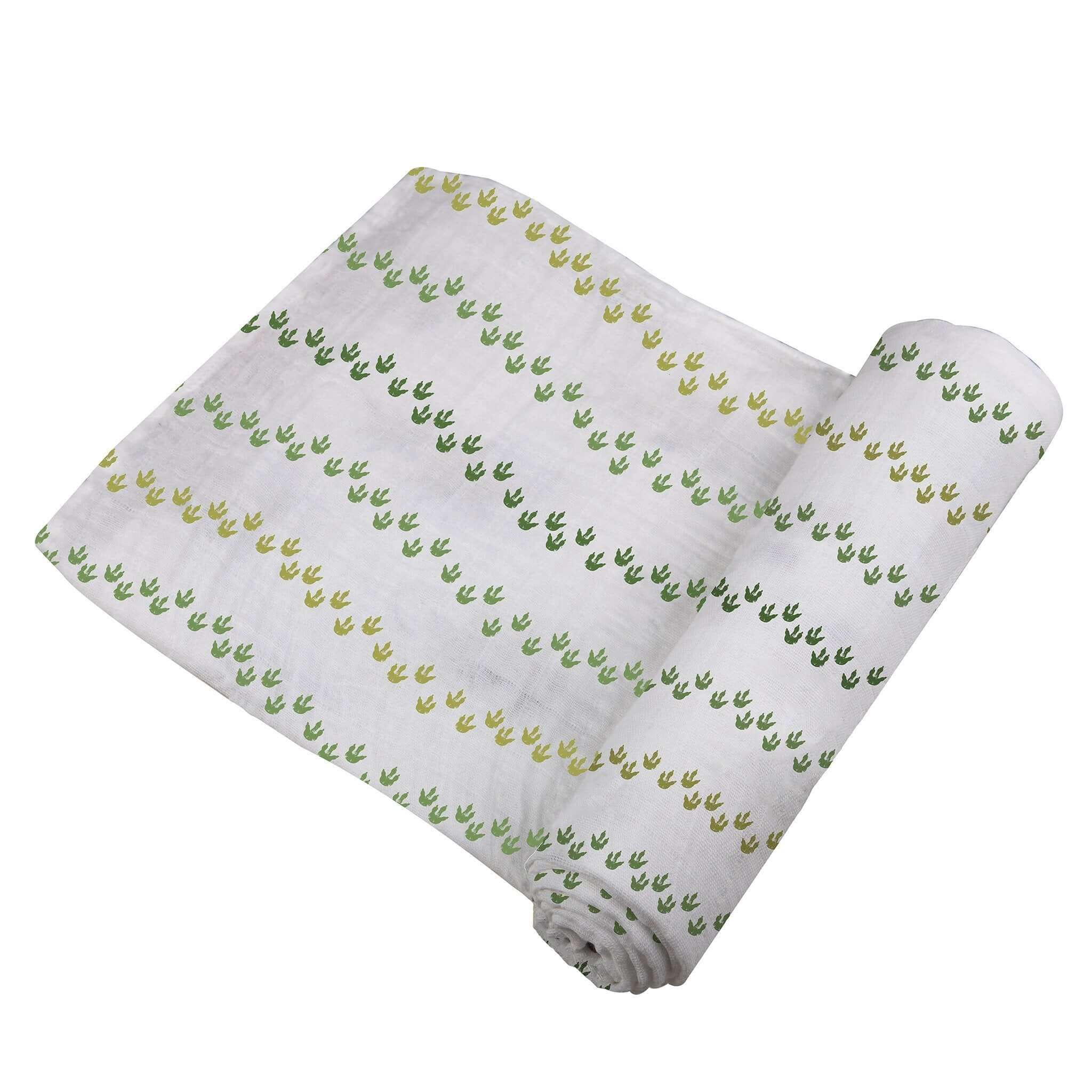 Dino Feet Cotton Muslin Swaddle featuring green and yellow dinosaur footprints on soft cotton fabric.