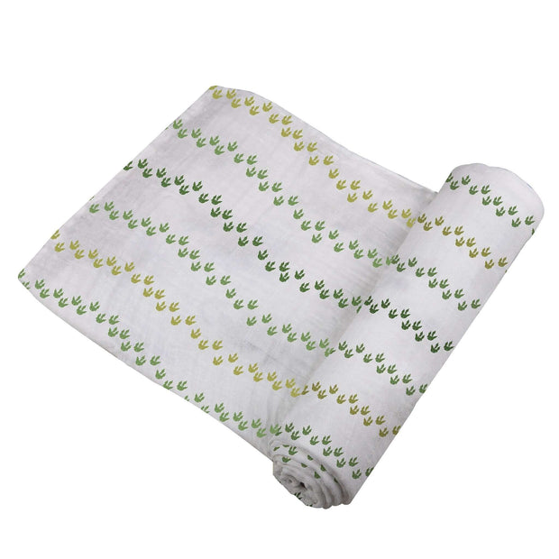 Dino Feet Cotton Muslin Swaddle featuring green and yellow dinosaur footprints on soft cotton fabric.