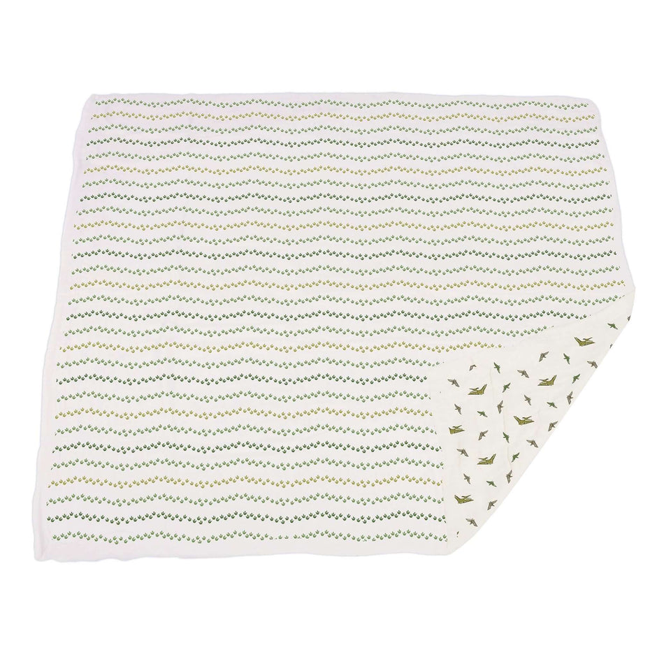 Dino Feet muslin blanket featuring a playful dinosaur print and a zigzag pattern on a soft fabric.